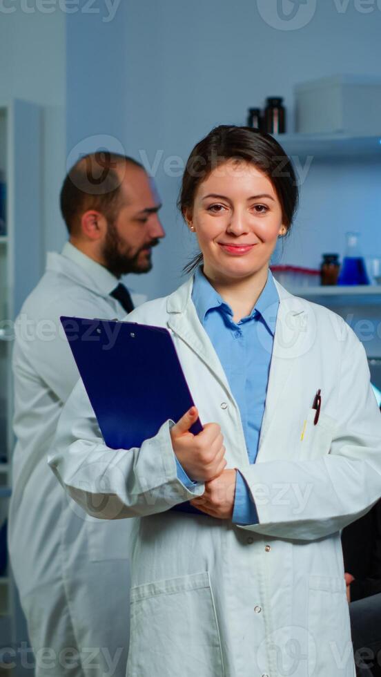 Portrait of scientist neurologist researcher looking at camera smiling while coworker discussing with patient in background about brain functions, nervous system, tomography scan working in laboratory photo