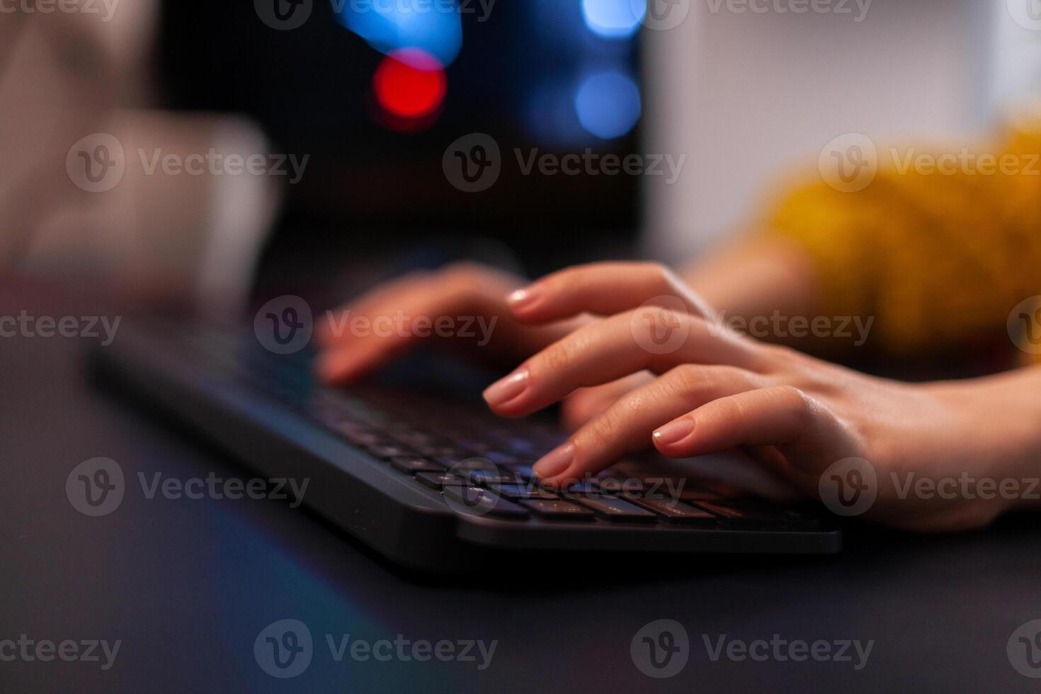 Closeup of gamer woman hand playing videogame during online gaming championship using RGB keyboard sitting at desk in streaming studio at home. Esport tournament. games competition photo