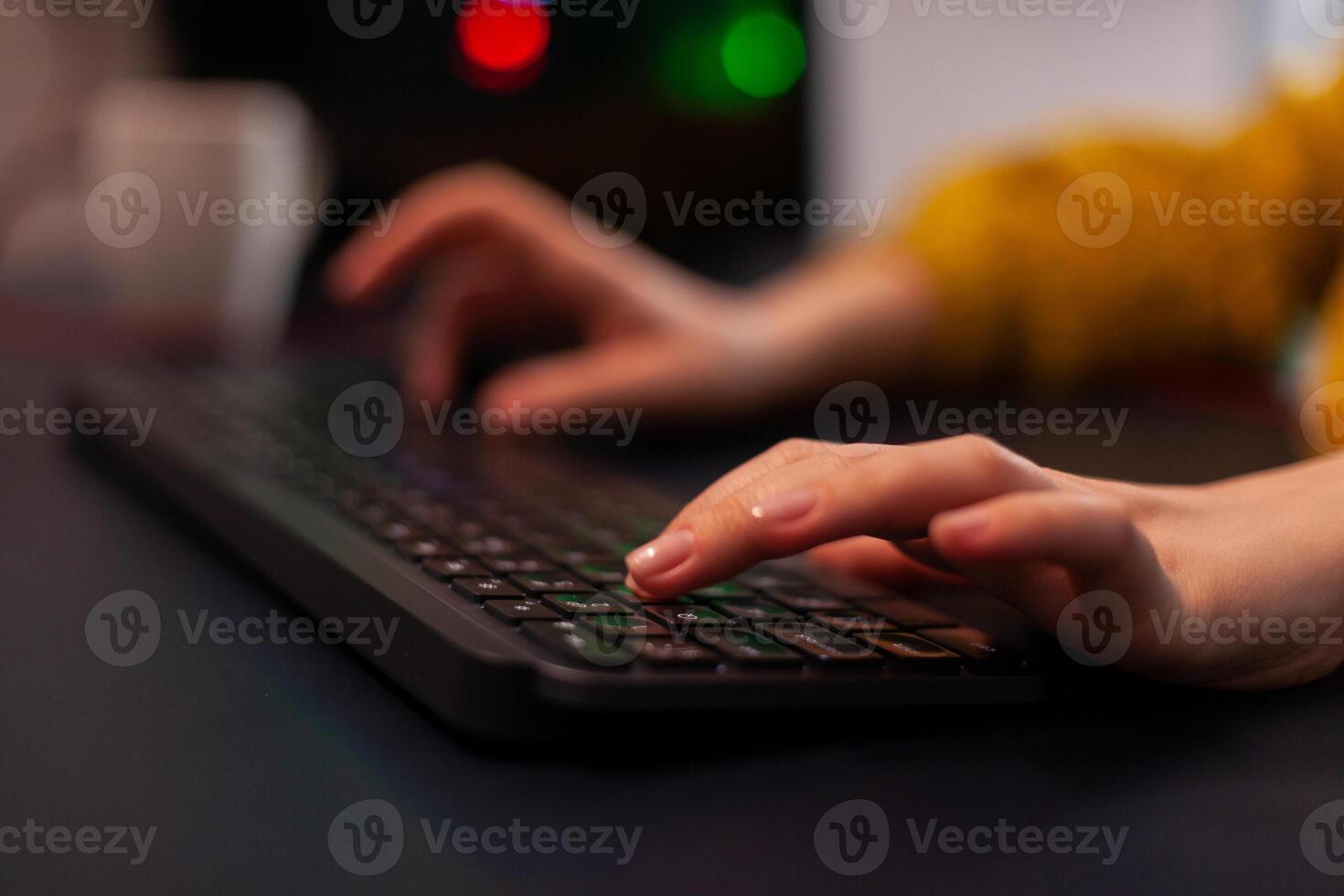 Closeup of player woman hand playing entertainment videogame during online streaming tournament using RGB keyboard sitting at desk in gaming studio at home. Esport championship photo