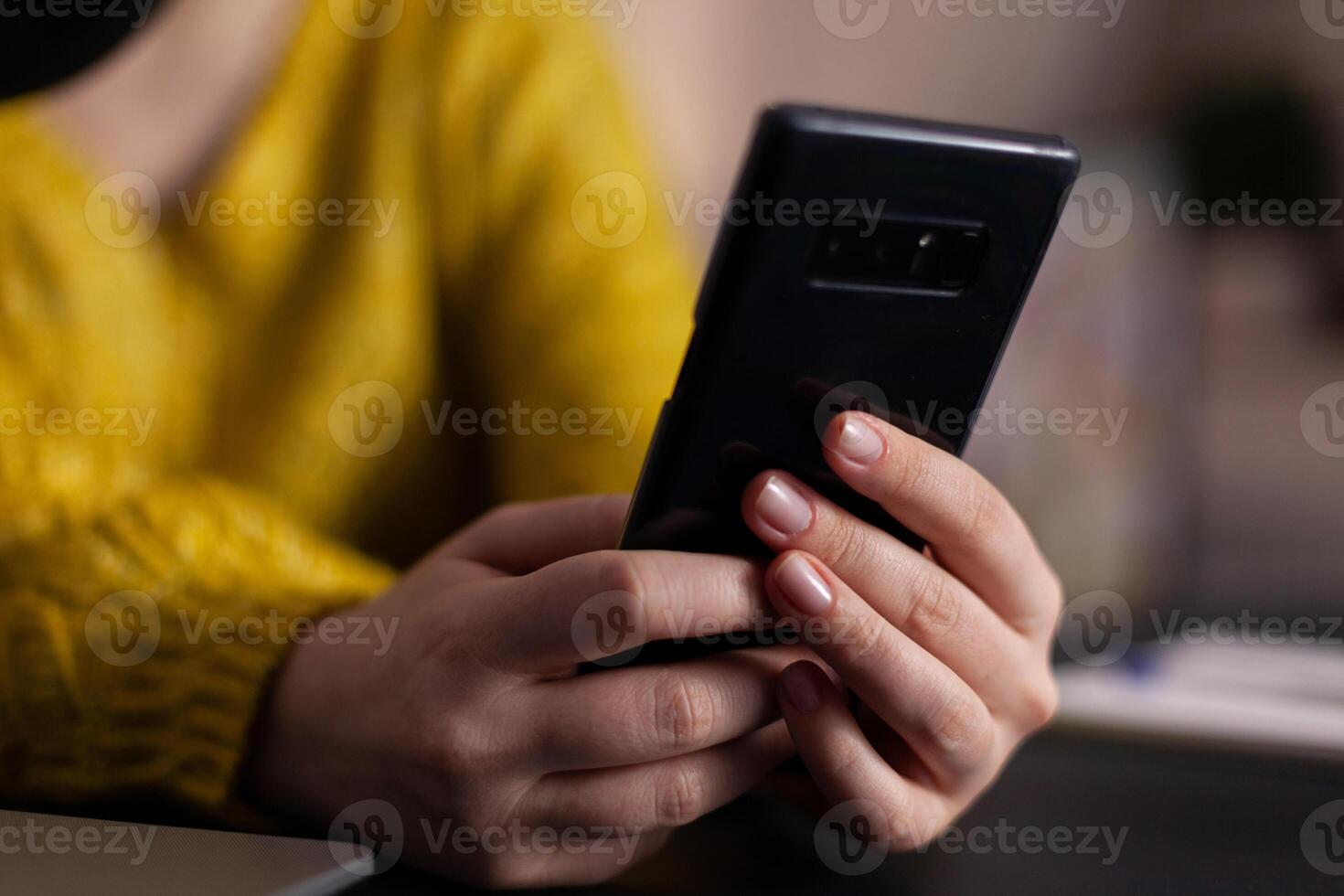 Closeup of social media vlogger with headset holding smartphone reading questions answering using production microphone sitting at desk in podcasting studio at home. On-air show photo