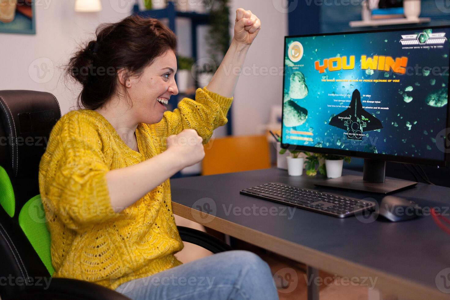 Excited happy competitive gamer woman winning space shooter videogames during online game championship in living room at home. Player performing cybersport tournament. game victory photo