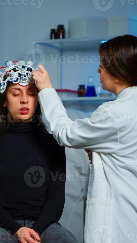 Ill woman visiting professional neurological research laboratory for neurology investigations. Doctor researcher adjusting EEG headset analyzing brain functions, descovering diagnosis of disease. photo