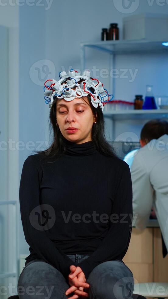 Specialist neurologist doctor taking notes on laptop asking patient's symptoms adjusting high tech eeg headset. Doctor researcher controlling EEG headset analyzing brain functions and health status photo