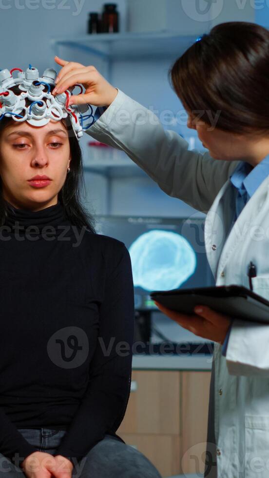 Professional doctor in neuroscience developing treatment for neurological diseases examining patient evolutions. Doctor researcher adjusting EEG headset analyzing brain functions and health status photo