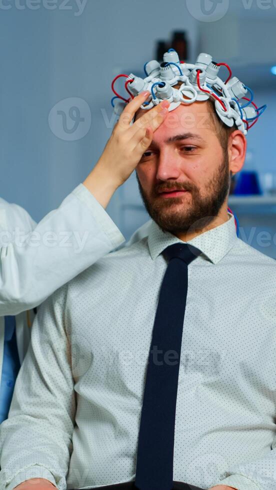 Neurologist doctor analysing brain of man and nervous system using brainwave scanning headset. Researcher using high tech developing neurological innovation monitoring side effects on monitor screen photo