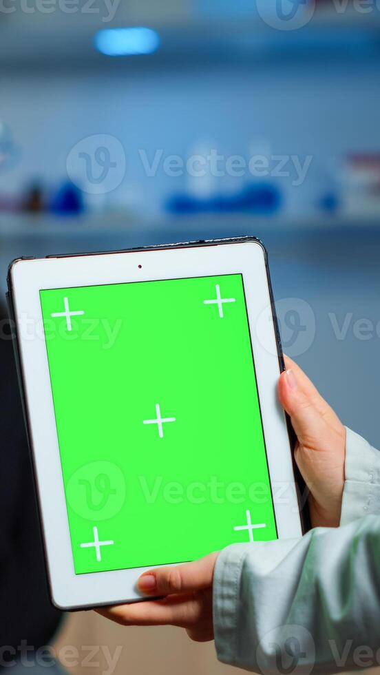 Health care researcher holding and looking at tablet with chroma key display in neurological lab. Team of scientists doing medical research reading on device with green screen, isolated mockup display photo