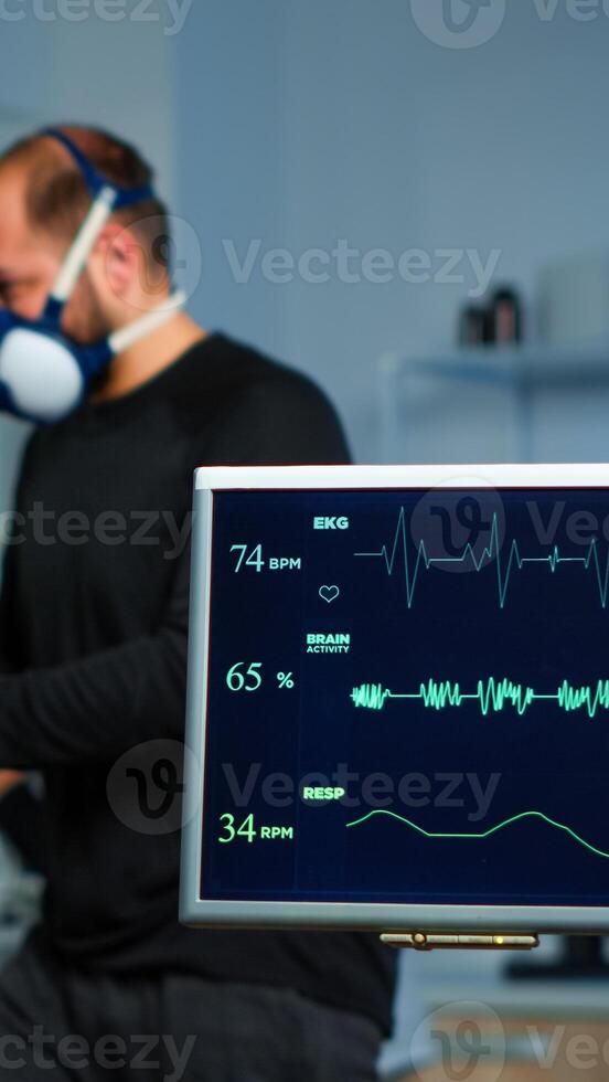 Team of medial researchers monitoring vo2 of man performance sports wearing mask running. Lab science doctor measuring endurance of sportsman while ekg scan runs on computer screen in laboratory photo