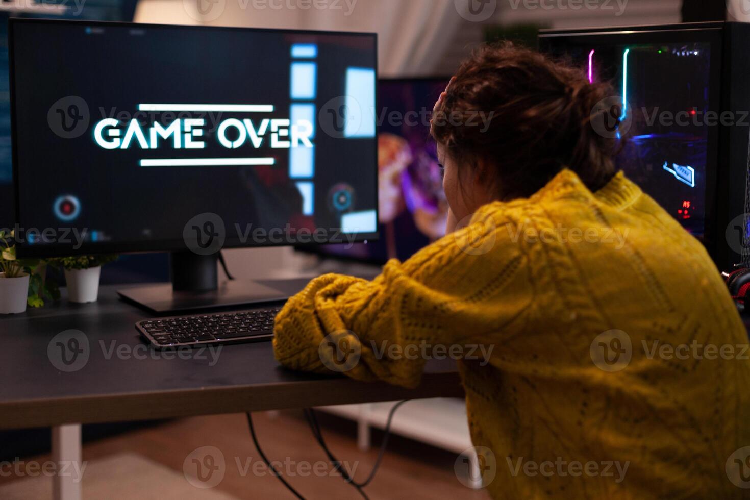 Angry streamer losing space shooter videogames during online entertainment competition at home in living room. Game over on computer screen. Player performing cybersport championship photo