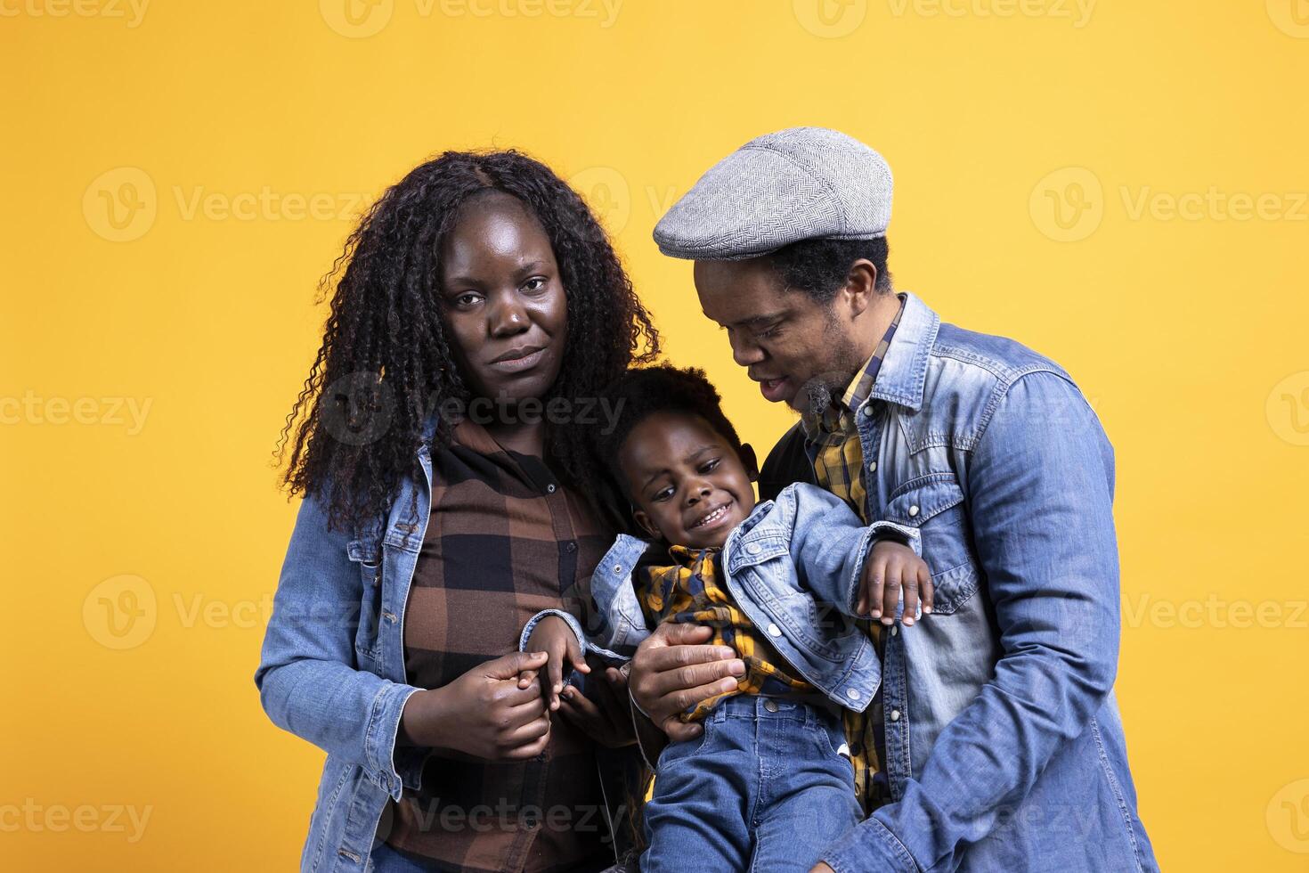African american positive couple posing with their young child in studio, smiling people hugging together. Happy affectionate mom and dad showing gratitude and respect on camera. photo