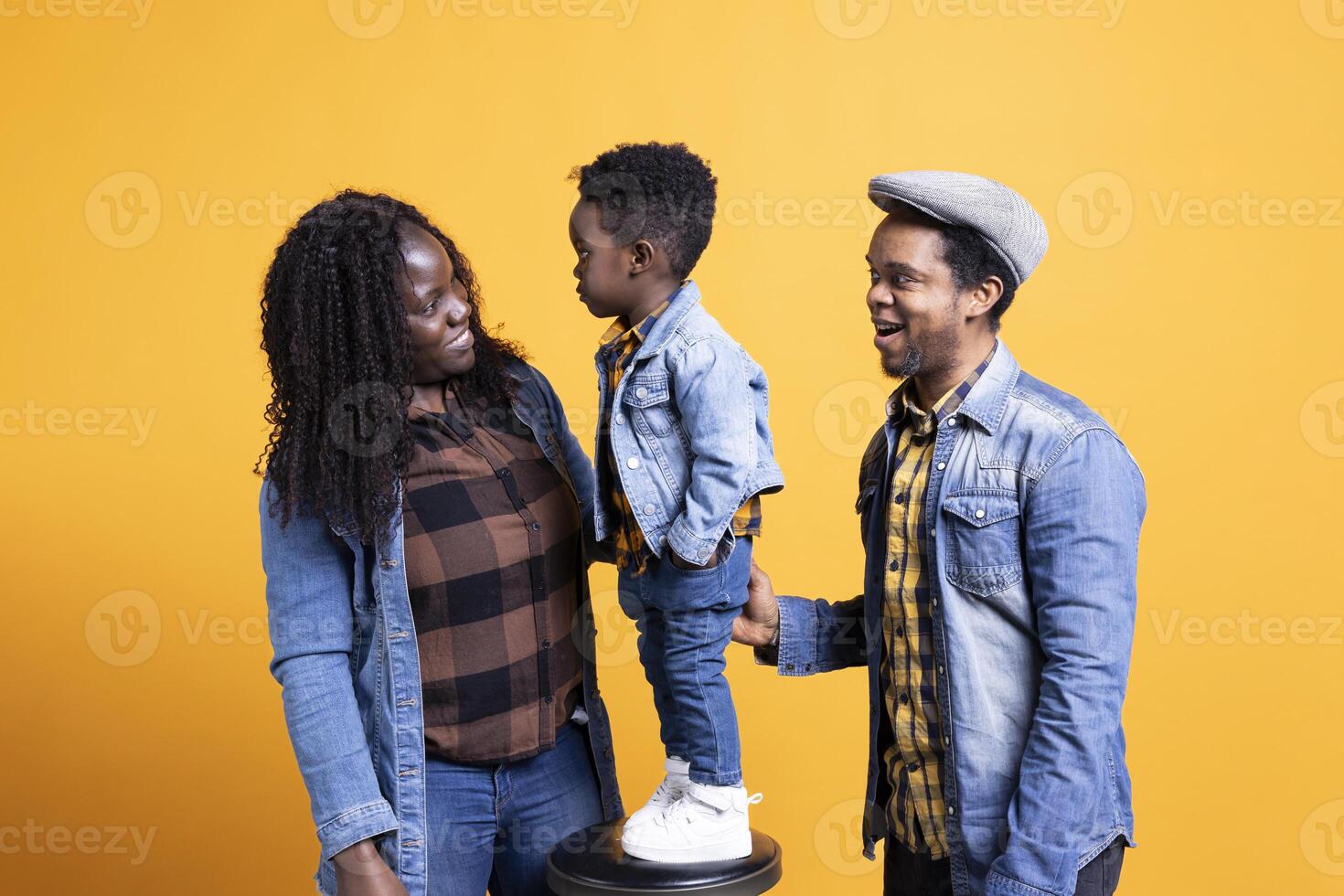 Portrait of african american family with a small boy posing in studio, showing affection and love towards each other and feeling happy. Grateful husband and wife holding their toddler. photo