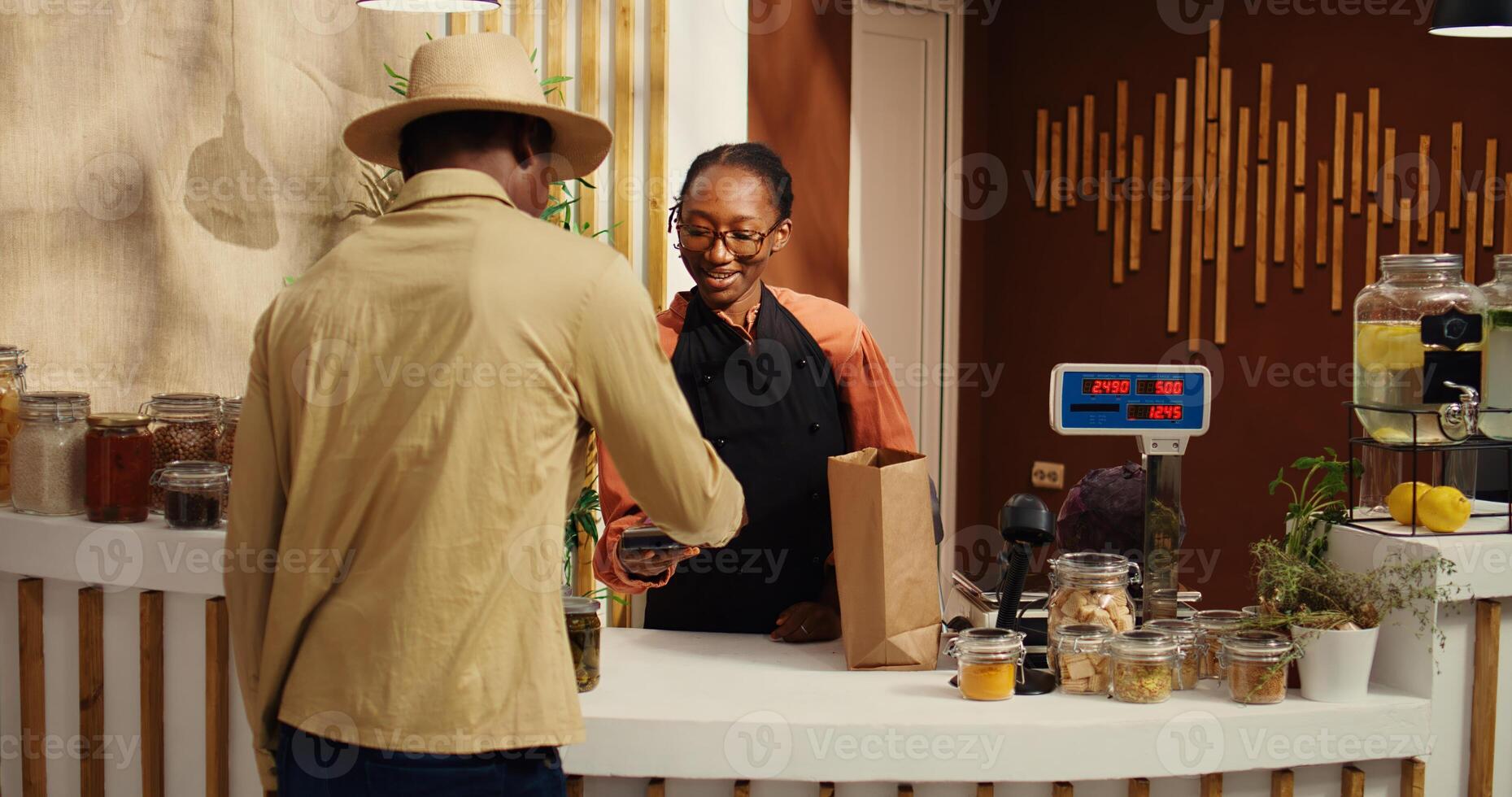 Vegan client buying ethically sourced fruits and vegetables at pos, shopping for locally grown additives free food in market. African american vendor scanning all products for customer. Camera 2. photo
