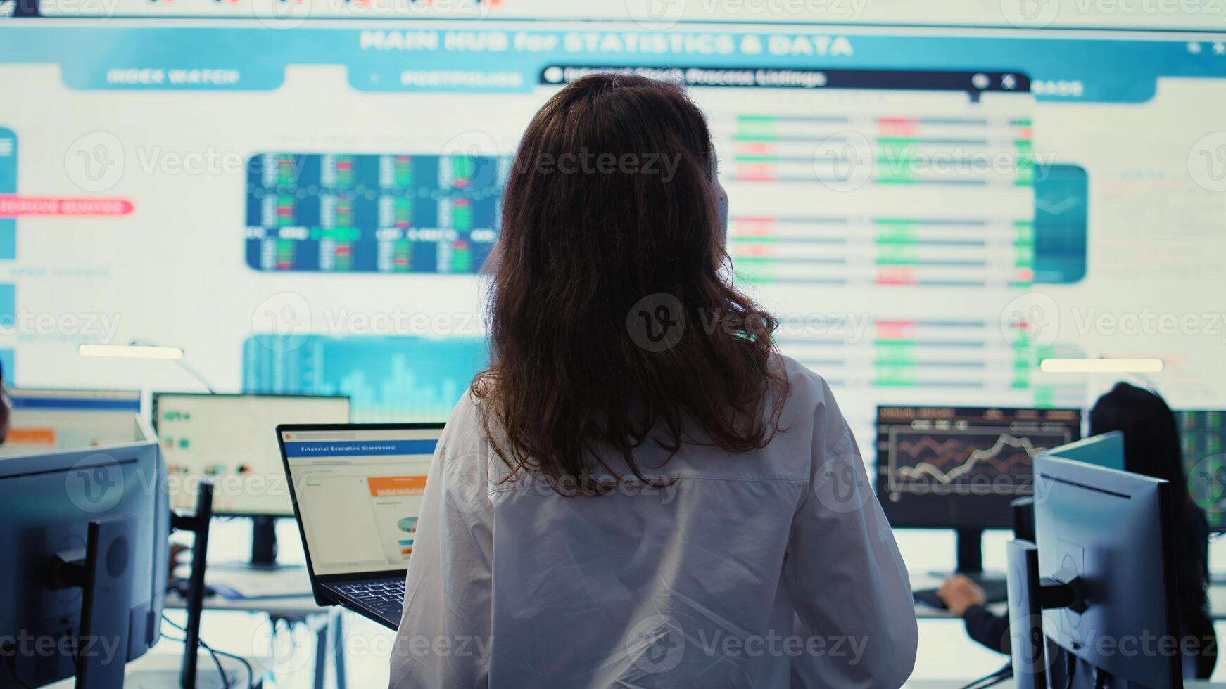 Project leader conducting a market research with a big screen in company headquarters office, ensuring enterprise progress. Financial manager studying the current organizational situation. Camera B. photo