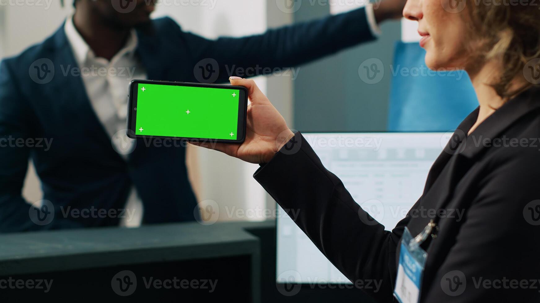 Store worker using smartphone with greenscreen template at cash register, working on commercial activity with male customer. Female employee looks at chromakey layout and copyspace. Camera A. photo