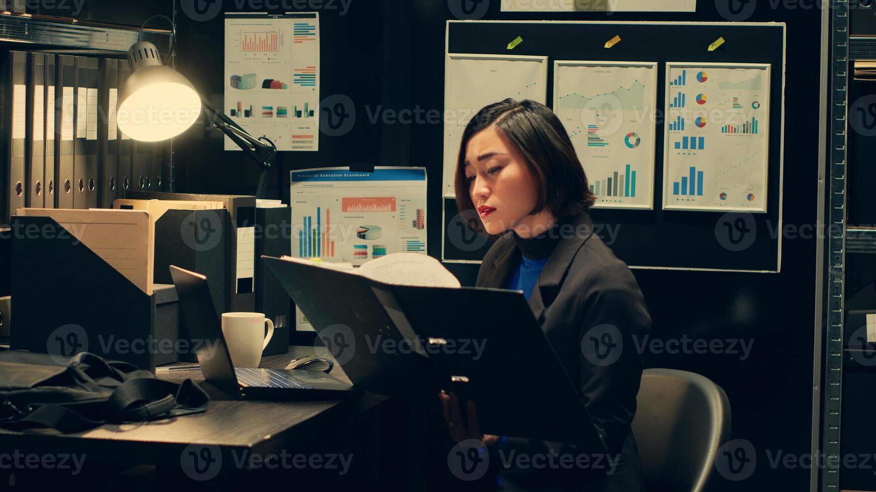 Asian law agent identifying potential missed details mentioned in archived documents, reading folder records to review discrepancies in archive room for investigation. Criminal expertise. Camera A. photo