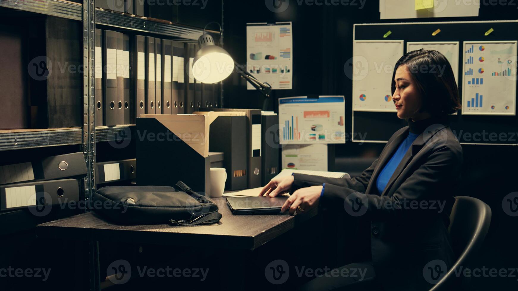 Private investigator finishes reading archived documents and connecting the dots, preparing for field work investigating. Asian agent creates timeline of events based on archived records. Camera B. photo