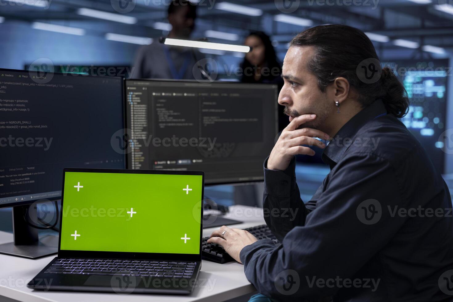 Man in server hub uses green screen laptop to find firewall misconfigurations affecting performance. Admin checks systems bottlenecks leading to sluggish data transfer rates using chroma ley notebook photo