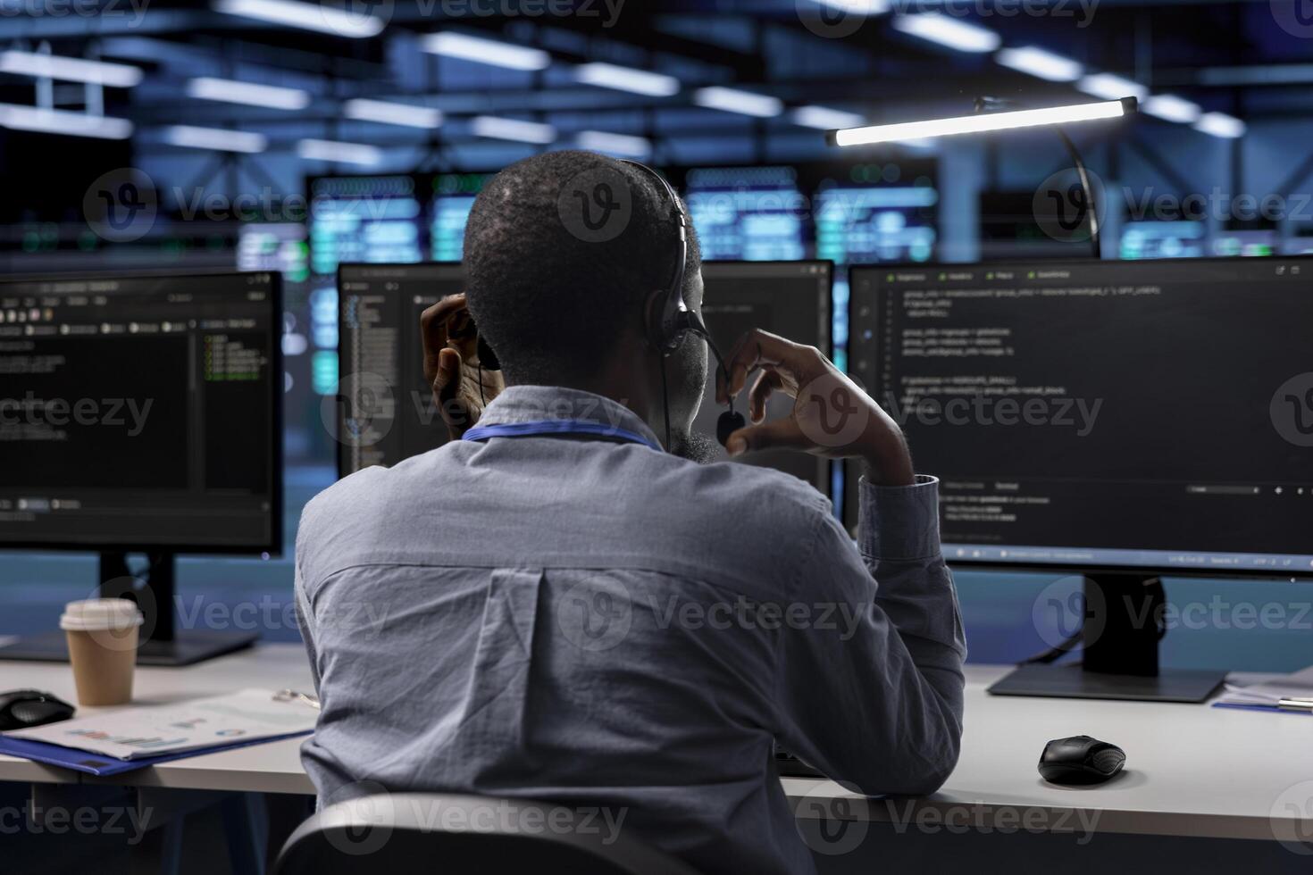 Technician in server room managing call center tasks, speaking into headset while monitoring multiple computer screens. Employee talking with clients through headphones mic photo