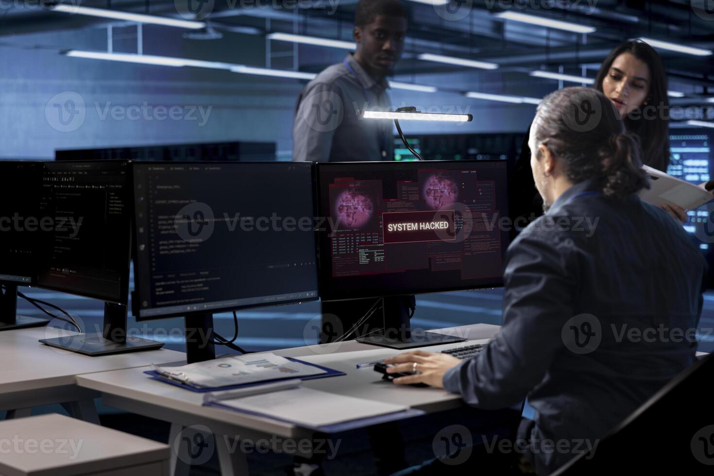 Computer scientist in server hub calling coworkers for help, trying to protect equipment from hacker. IT specialist in data center facility requesting assistance to fix security breach alert photo