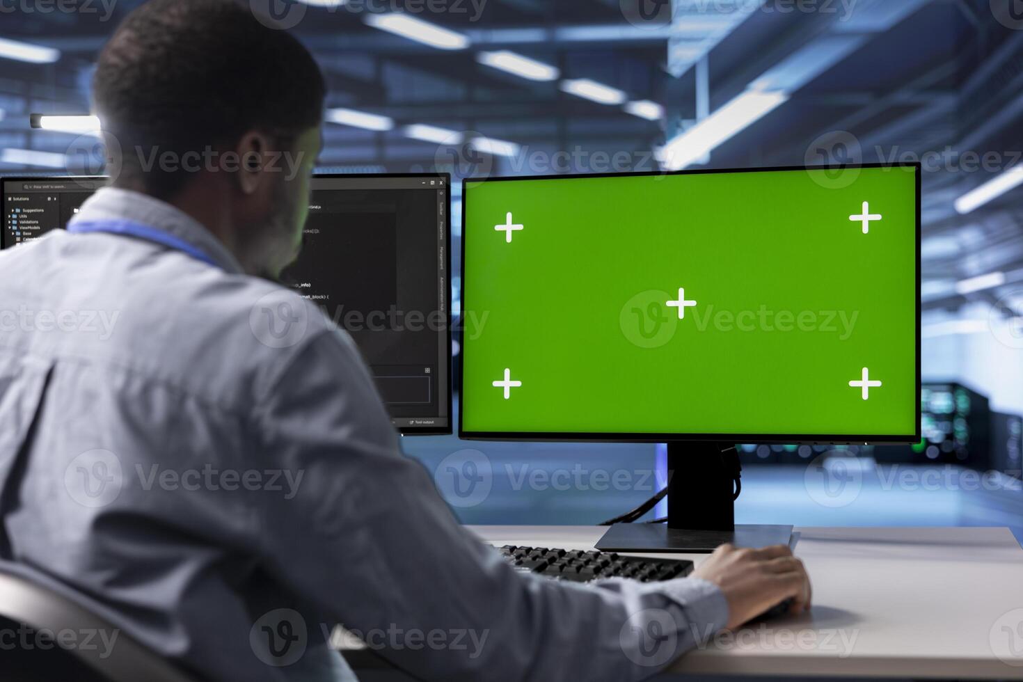 African american man in data center using green screen computer to check for server performance issues. IT expert in server hub fixing errors slowing down hardware using chroma key PC photo