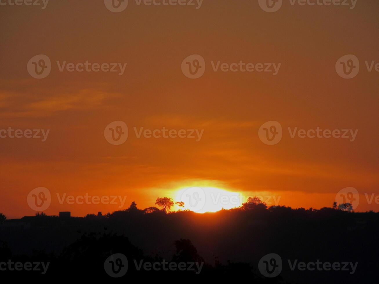 The beautiful appearance of sun rising behind clouds and sun rays coming down to a dense forest photo