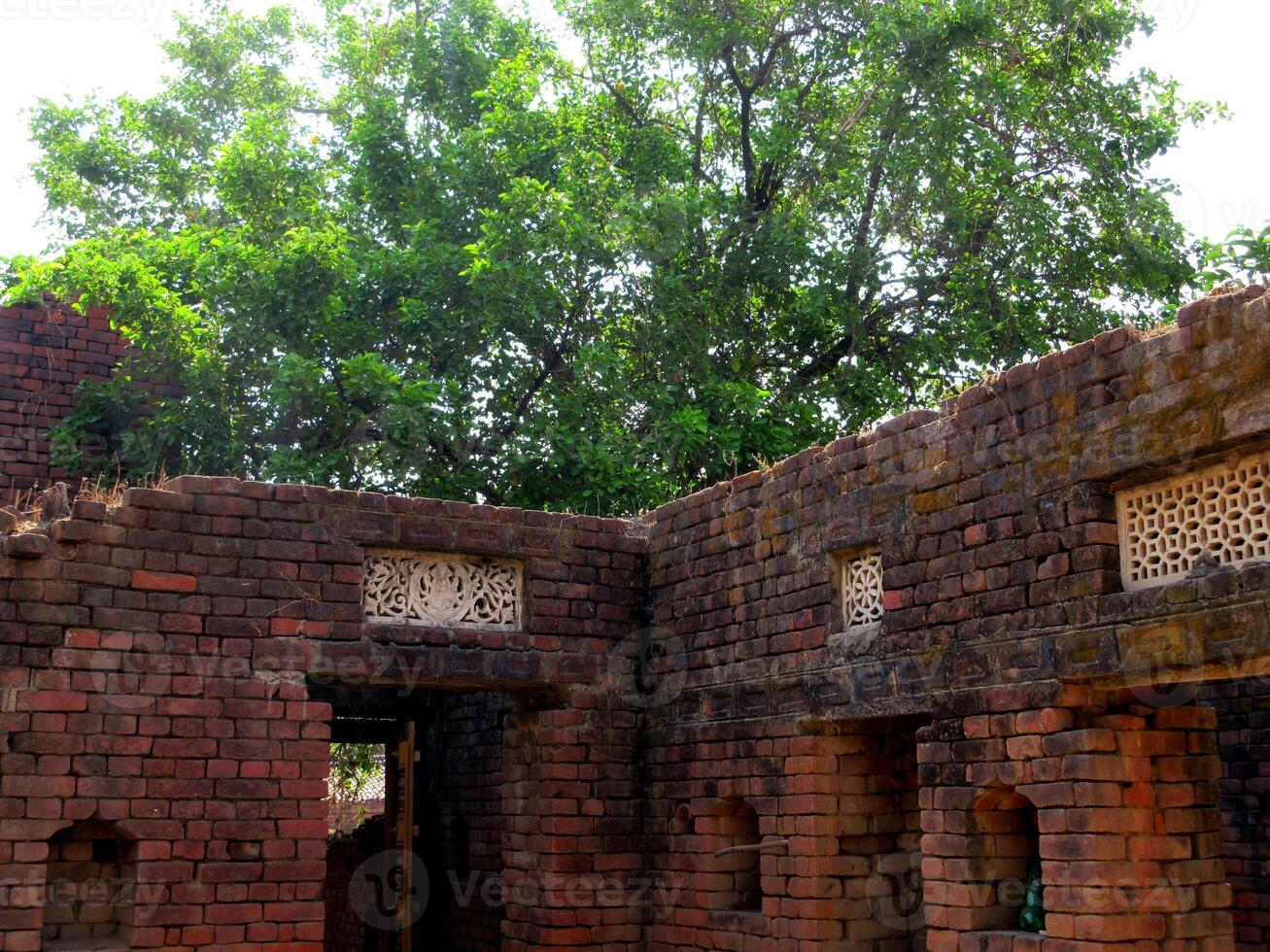 A village farmhouse with an open roof at the centre with brick walls photo