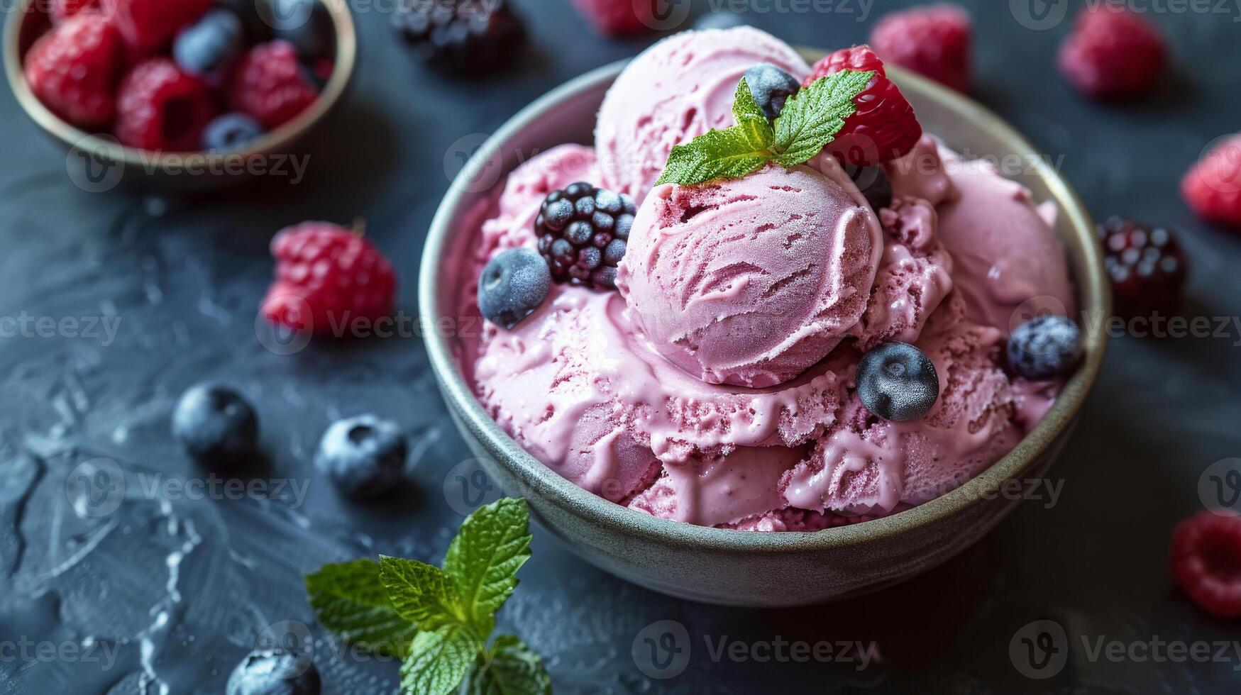 A bowl of vibrant berry ice cream topped with fresh blueberries, raspberries, and a mint leaf. The frozen dessert on a dark table, top view. Perfect for summer. photo