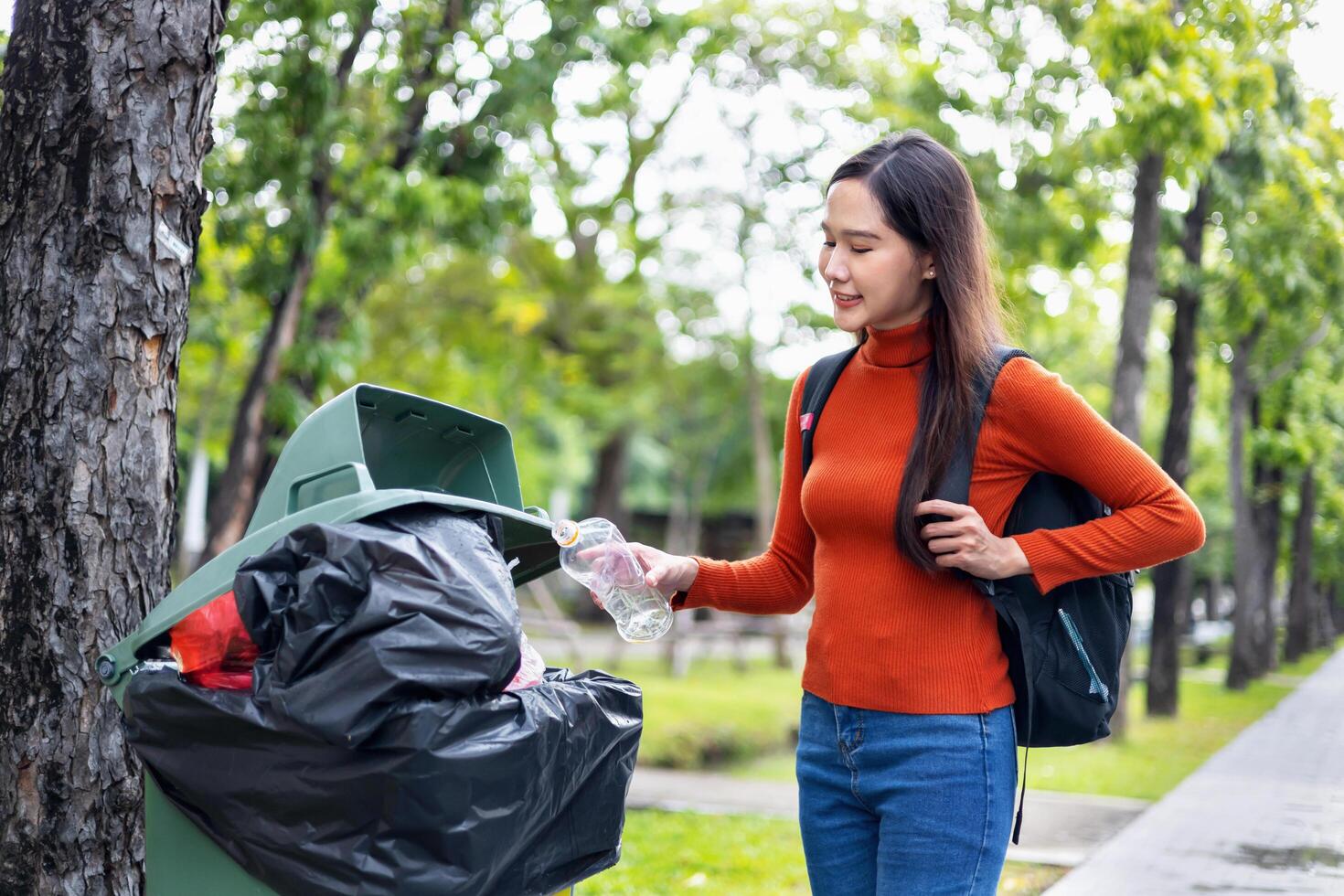 woman is throwing away trash and holding a bottle photo