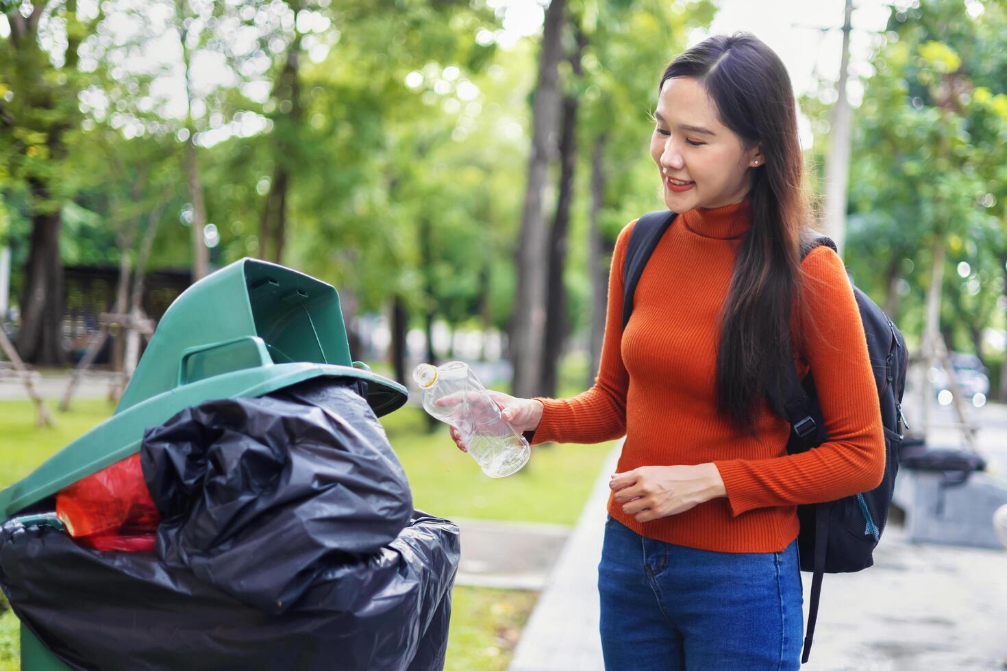 woman is throwing away trash and holding a bottle photo