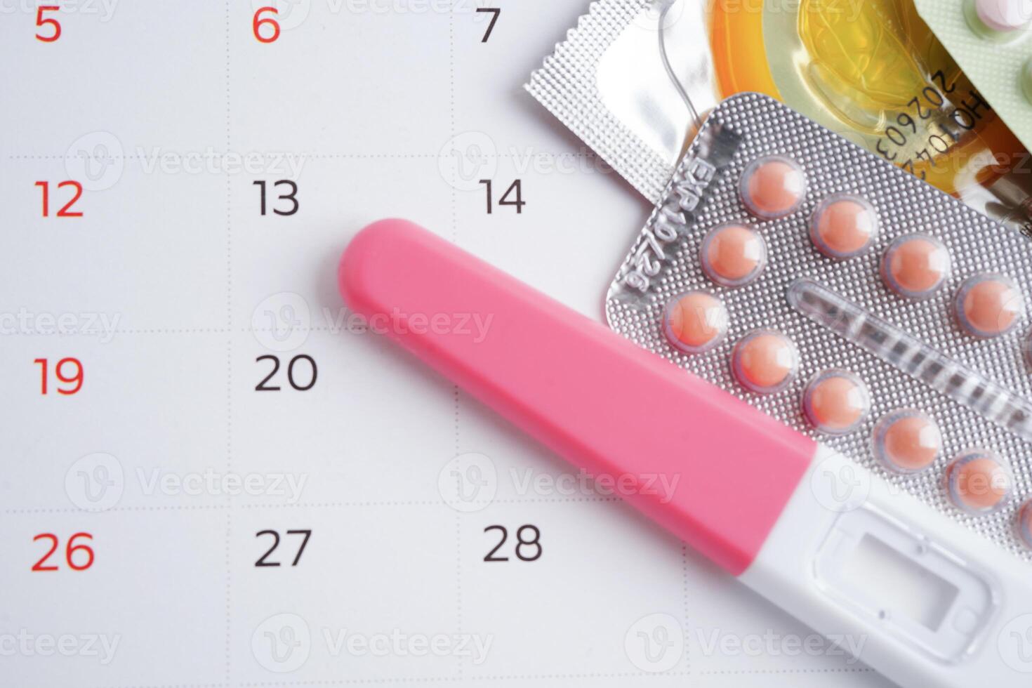 Pregnancy test with birth control pills and condom for female on calendar, ovulation day. photo