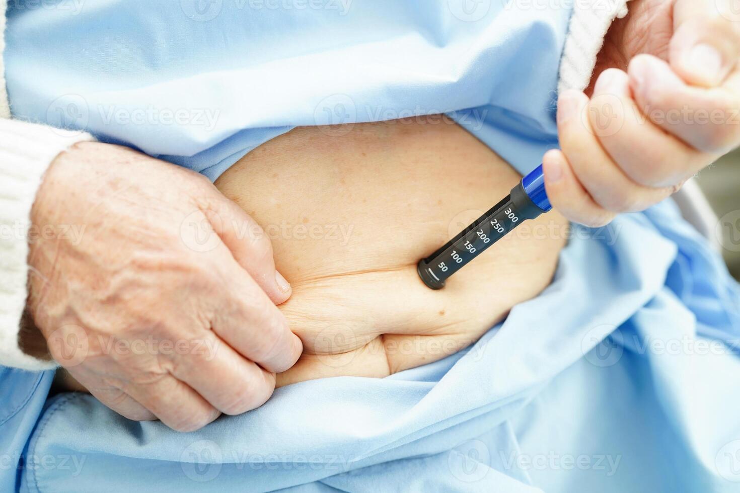 Asian senior woman making injection insulin pen in belly to treatment diabetes. photo
