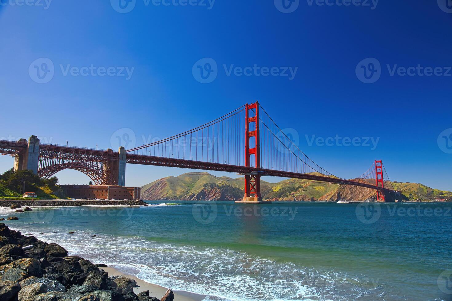 Famous Golden Gate Bridge in San Francisco, California with Beach on a Sunny Blue Sky Day. Concept for Travel Destination, City Guide, Visit California and Famous Landmarks Around the World. photo