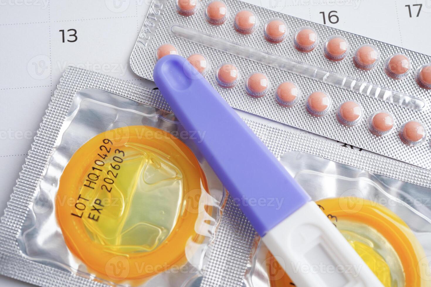 Pregnancy test with birth control pills and condom for female on calendar, ovulation day. photo