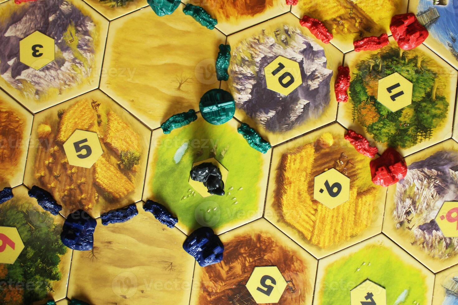 Mozyr, Belarus, April 01 2024. A catan board game blue, green and red chips of players on the field. Blocked resource hex by bandits. The longest highway and the largest army. Extra Points photo