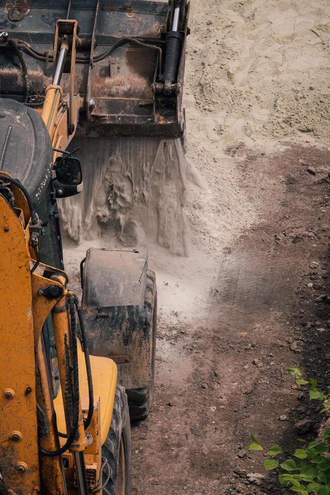 Sand pours from the bucket of the tractor Lviv Ukraine 20.05.24 photo