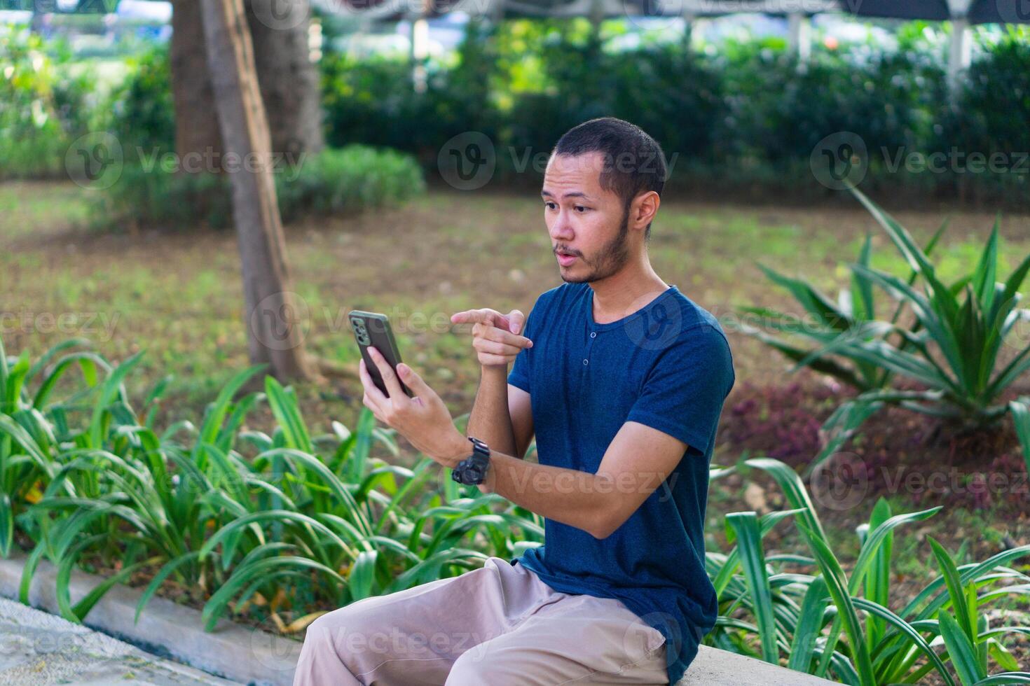 Young asian men with blue shirt shock and stressed while playing smartphone on the park outdoor photo