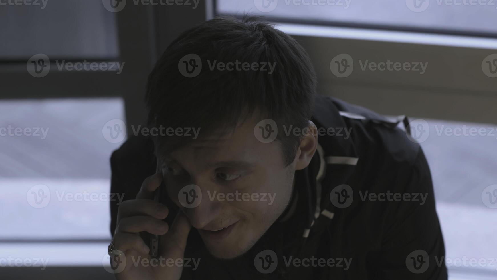 Man is calling excitedly on phone. Stock. Close-up of man calling and talking on phone. Man is making phone call on background of windows photo