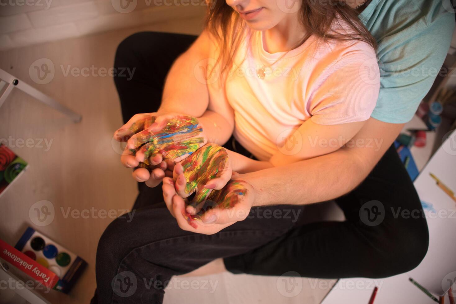 Two lovers draw with paints. Two lovers draw with paints. Hands are covered with paint . photo