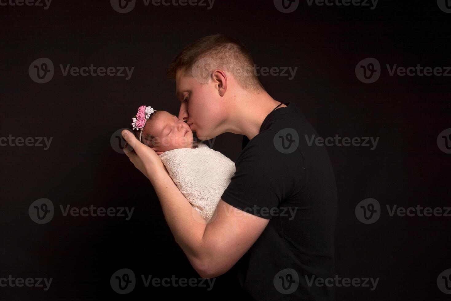 Red-haired father and newborn daughter on a black background. photo
