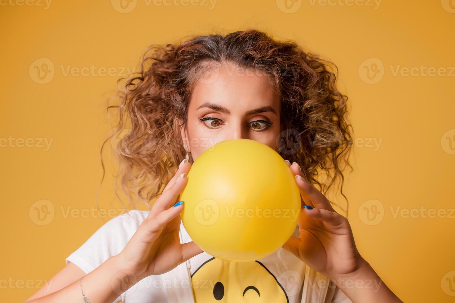 girl inflates a balloon on a yellow background photo