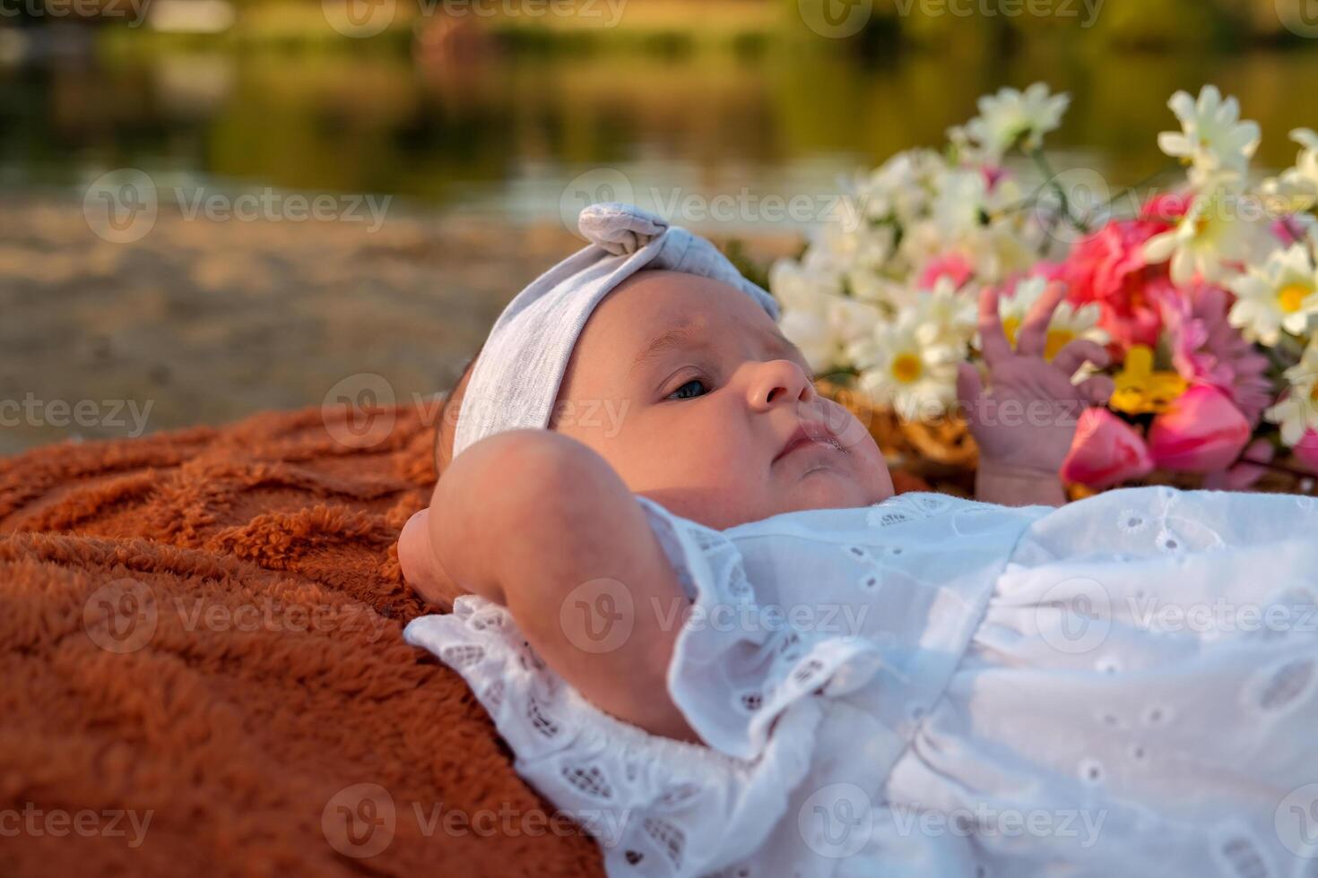 newborn baby girl lies on the beach. in a white dress. photo