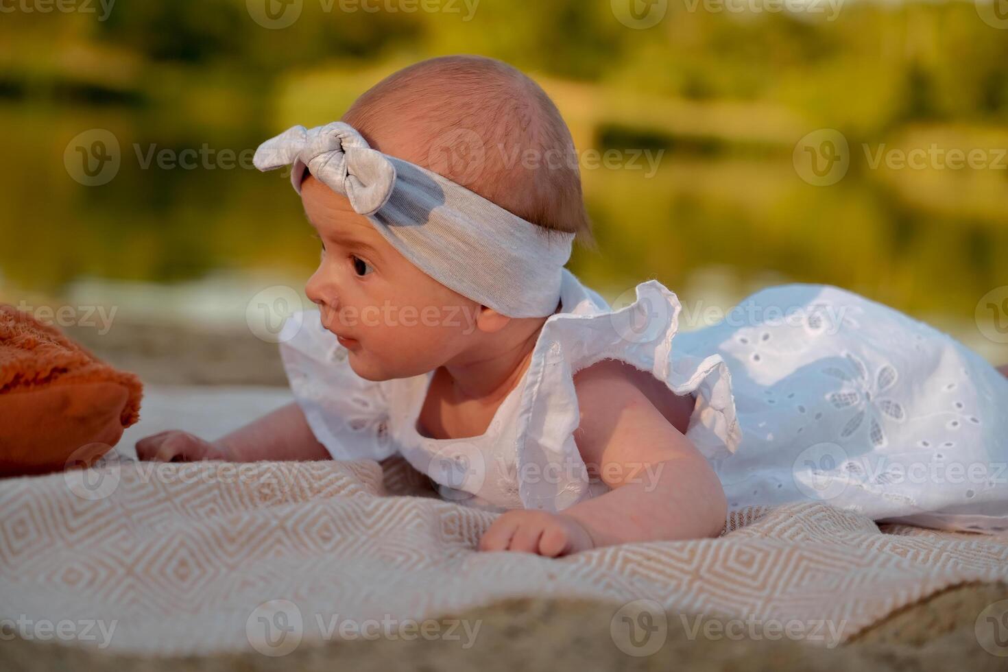 newborn baby girl lies on the beach. in a white dress. photo