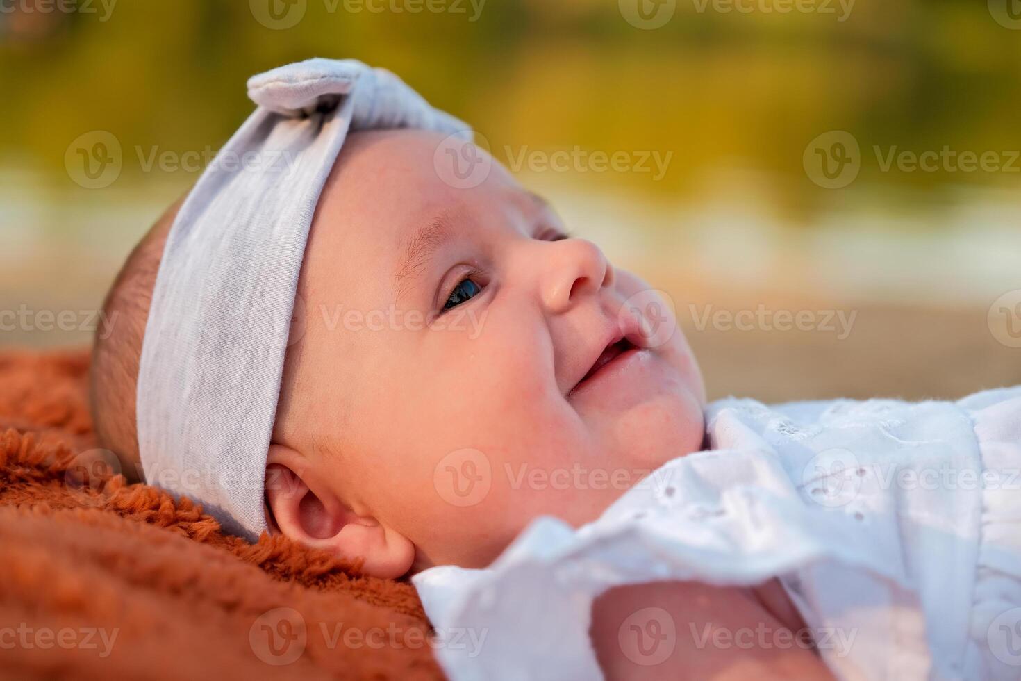 newborn baby girl lies on the beach. in a white dress. photo