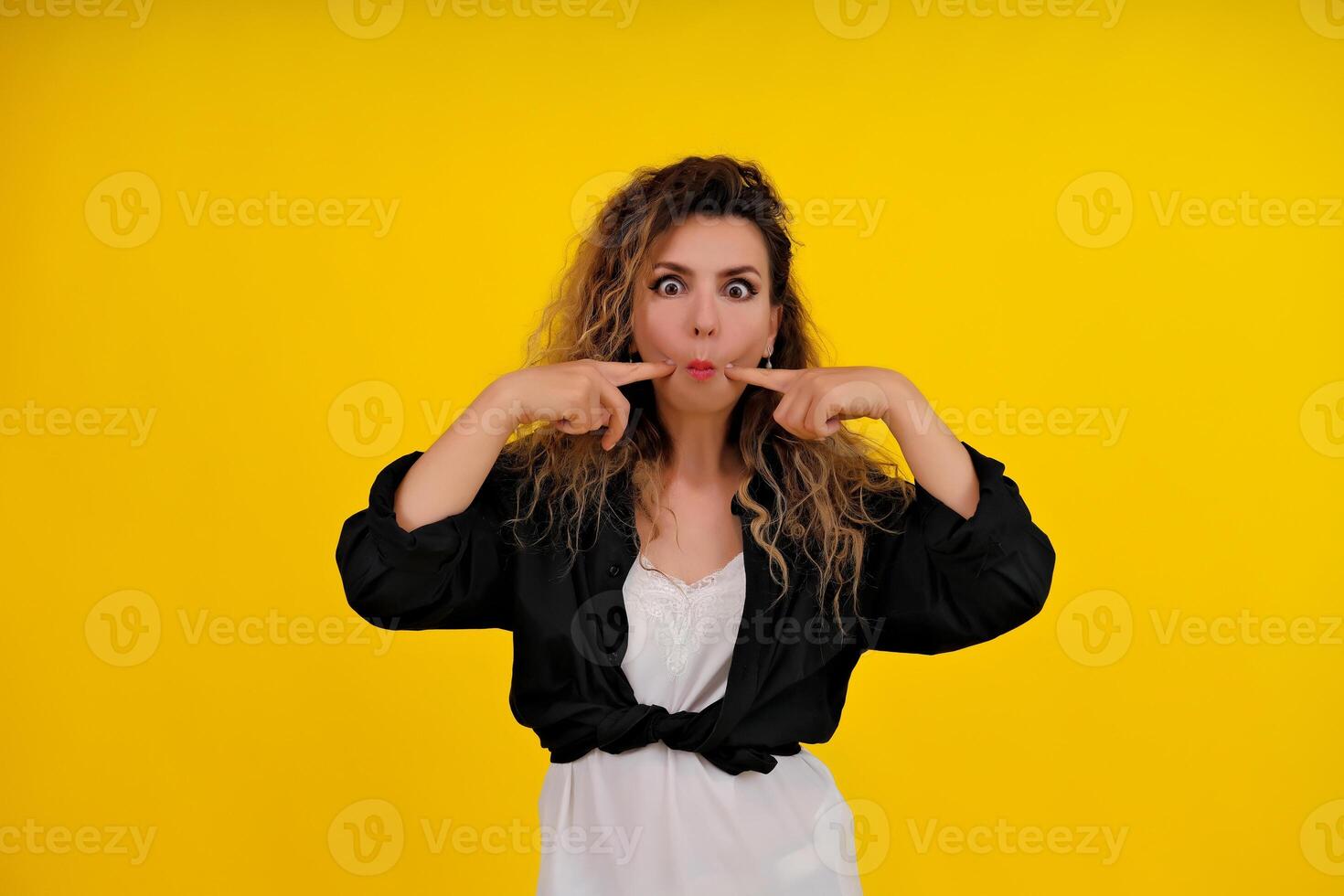 Close-up portrait of a beautiful girl on a yellow background. woman shows surprise. Shocked surprised stunned. positive human emotions photo
