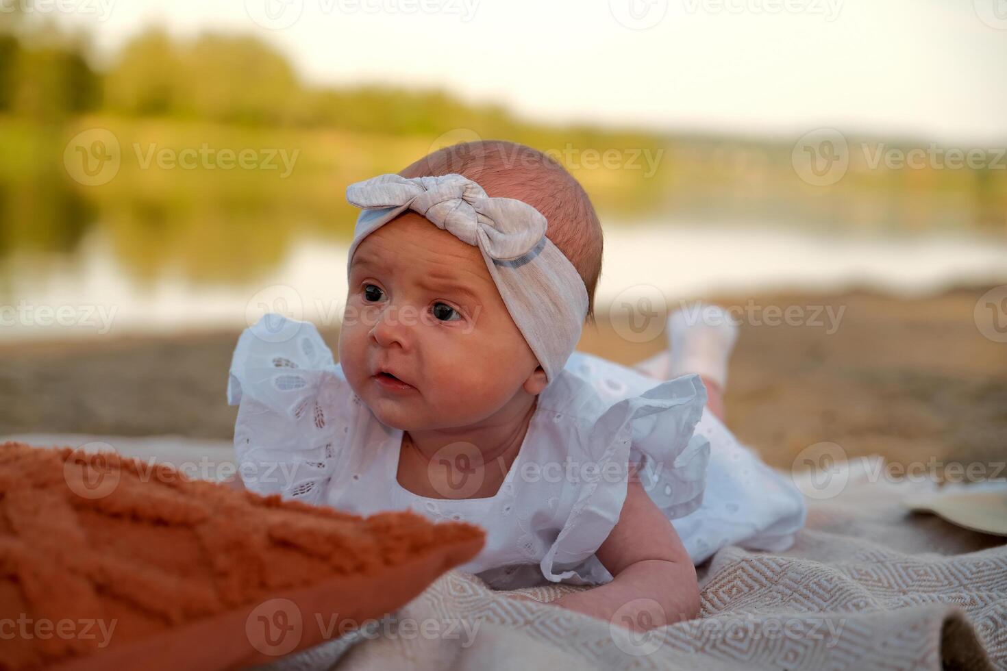 newborn baby girl lies on the beach. in a white dress. photo