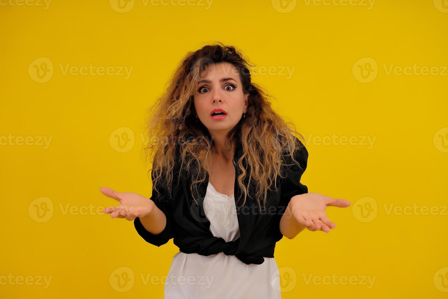 Close-up portrait of a beautiful girl on a yellow background. woman shows surprise. Shocked surprised stunned. positive human emotions photo