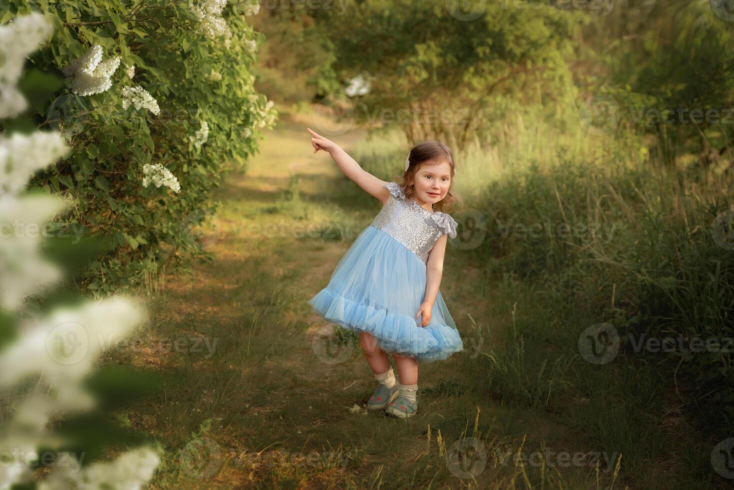 a child in a blue dress plays in the park. plays in the forest. girl with a basket collects flowers. photo