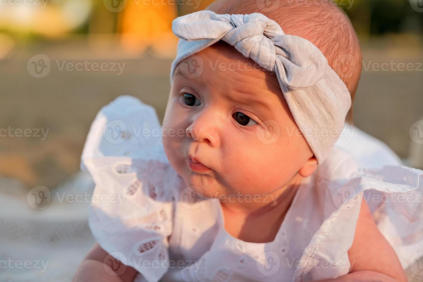 newborn baby girl lies on the beach. in a white dress. photo