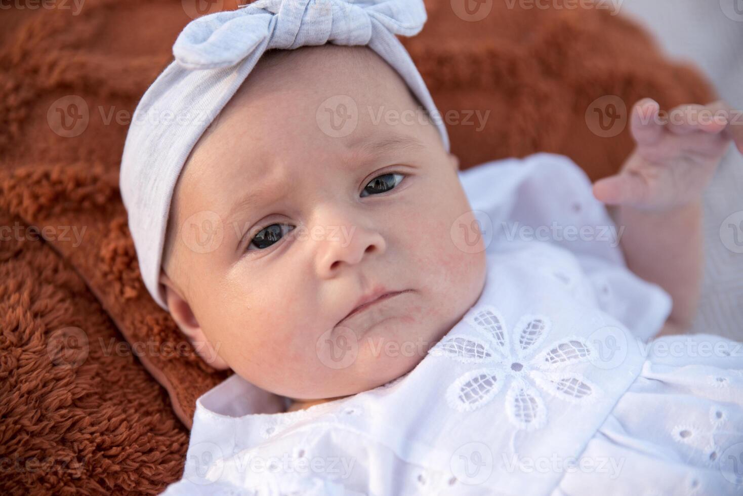 a newborn child lies on a blanket, on the shore. flowers lie nearby. photo