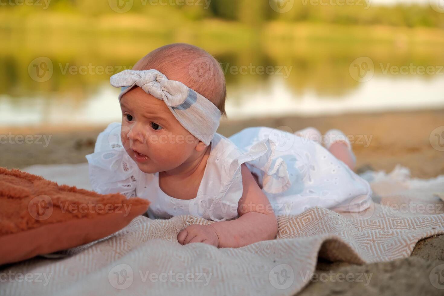 newborn baby girl lies on the beach. in a white dress. photo