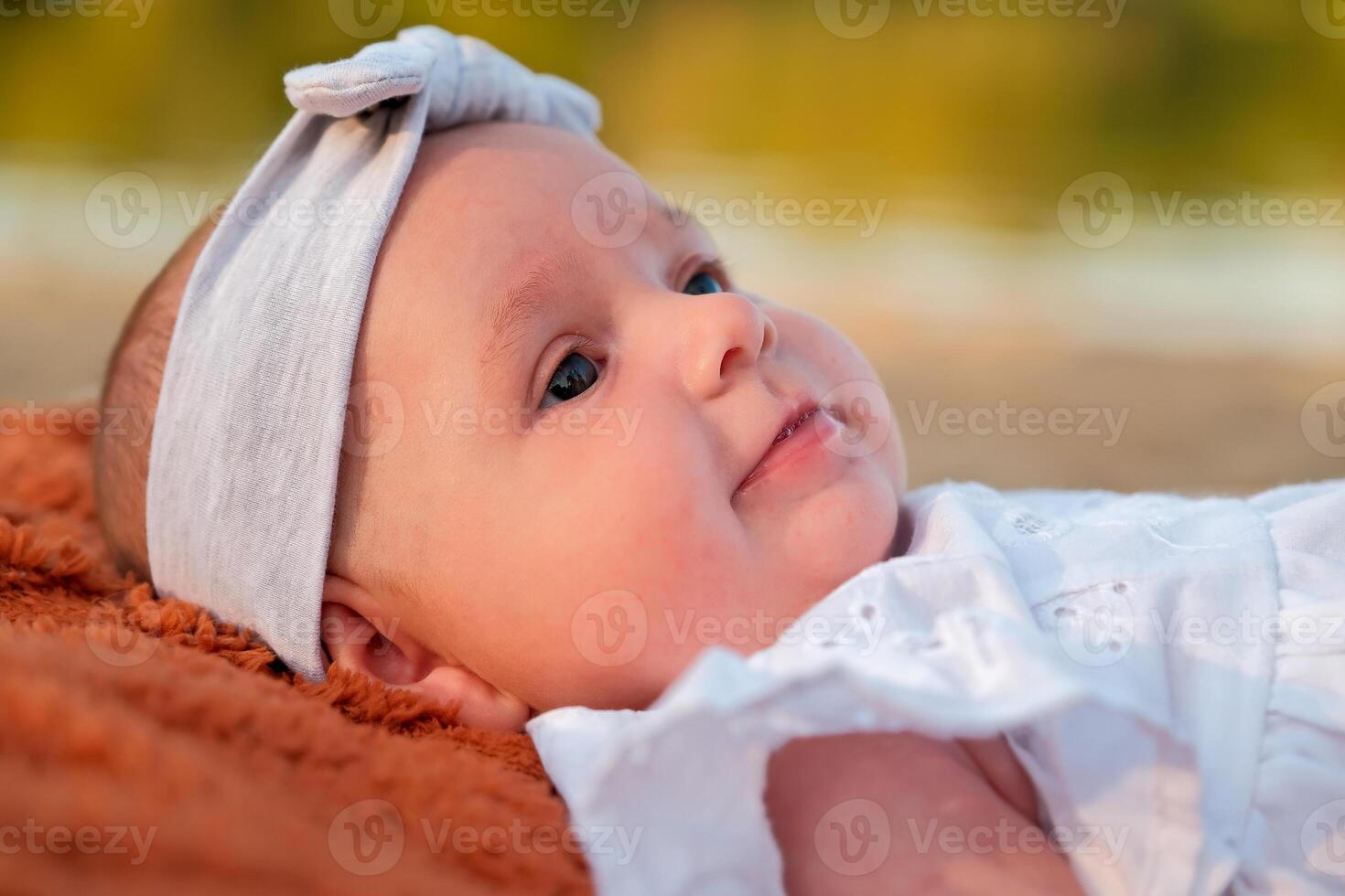 newborn baby girl lies on the beach. in a white dress. photo